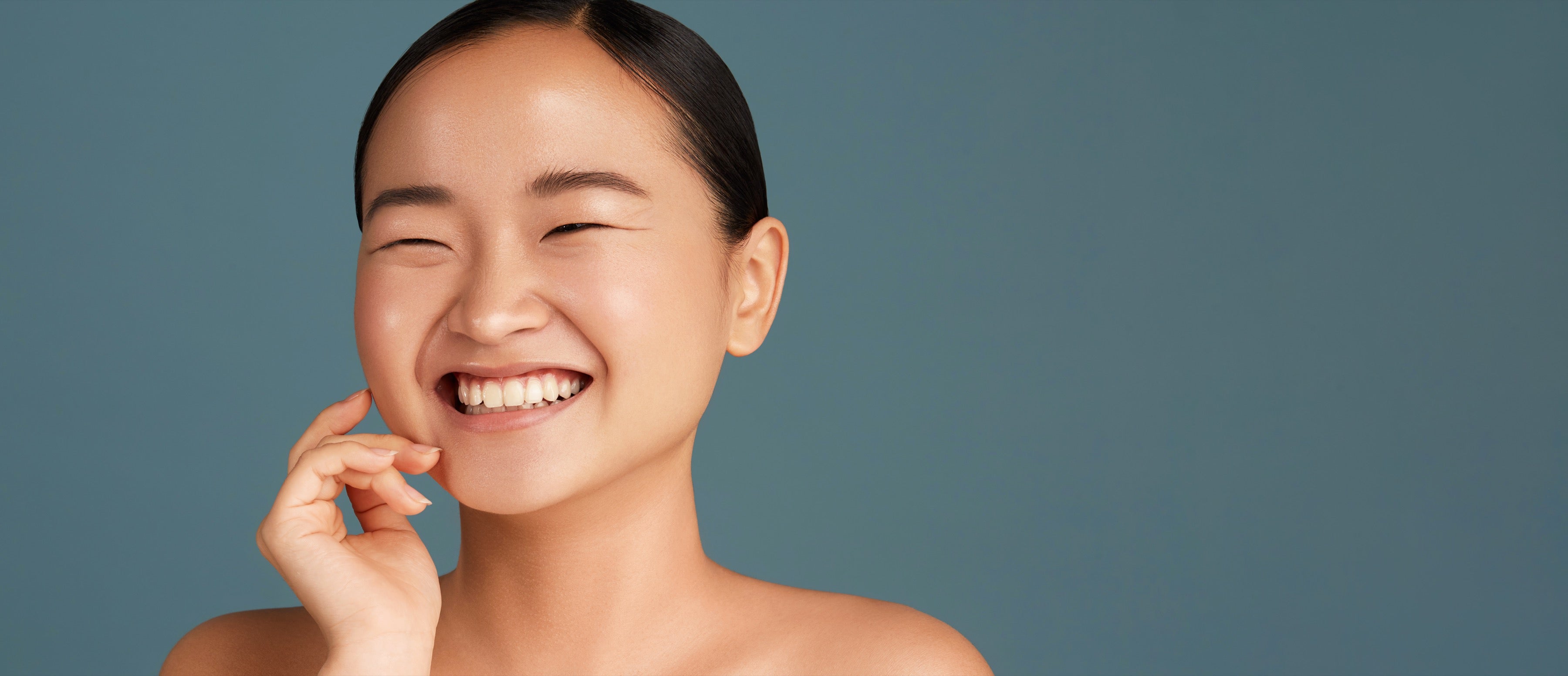 Ragazza sorridente con la pelle luminosa, su fondo blu-verde